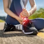 A,Woman,Jogging,On,A,Trail,Holds,Her,Painful,Ankle
