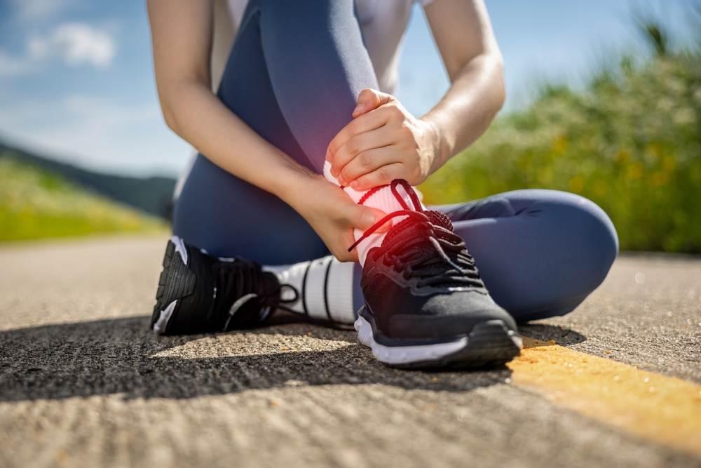 A,Woman,Jogging,On,A,Trail,Holds,Her,Painful,Ankle